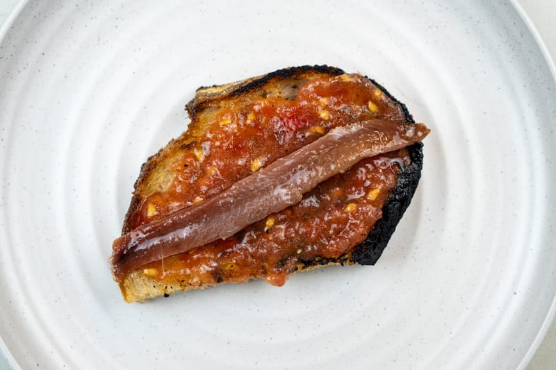 Adding the anchovy to the tomato toast
